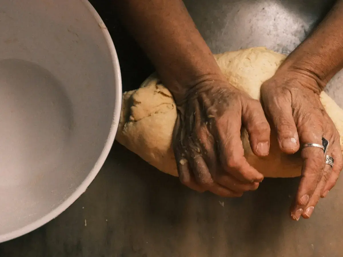Hands kneading dough on a kitchen work surface